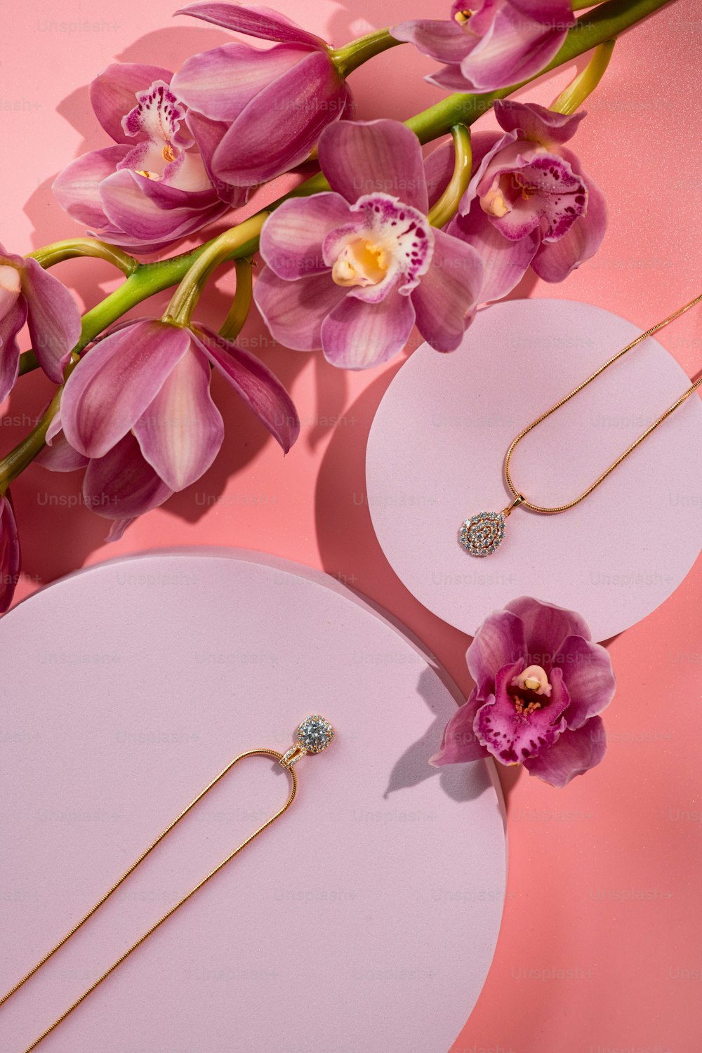 a close up of a pair of earrings on a pink surface