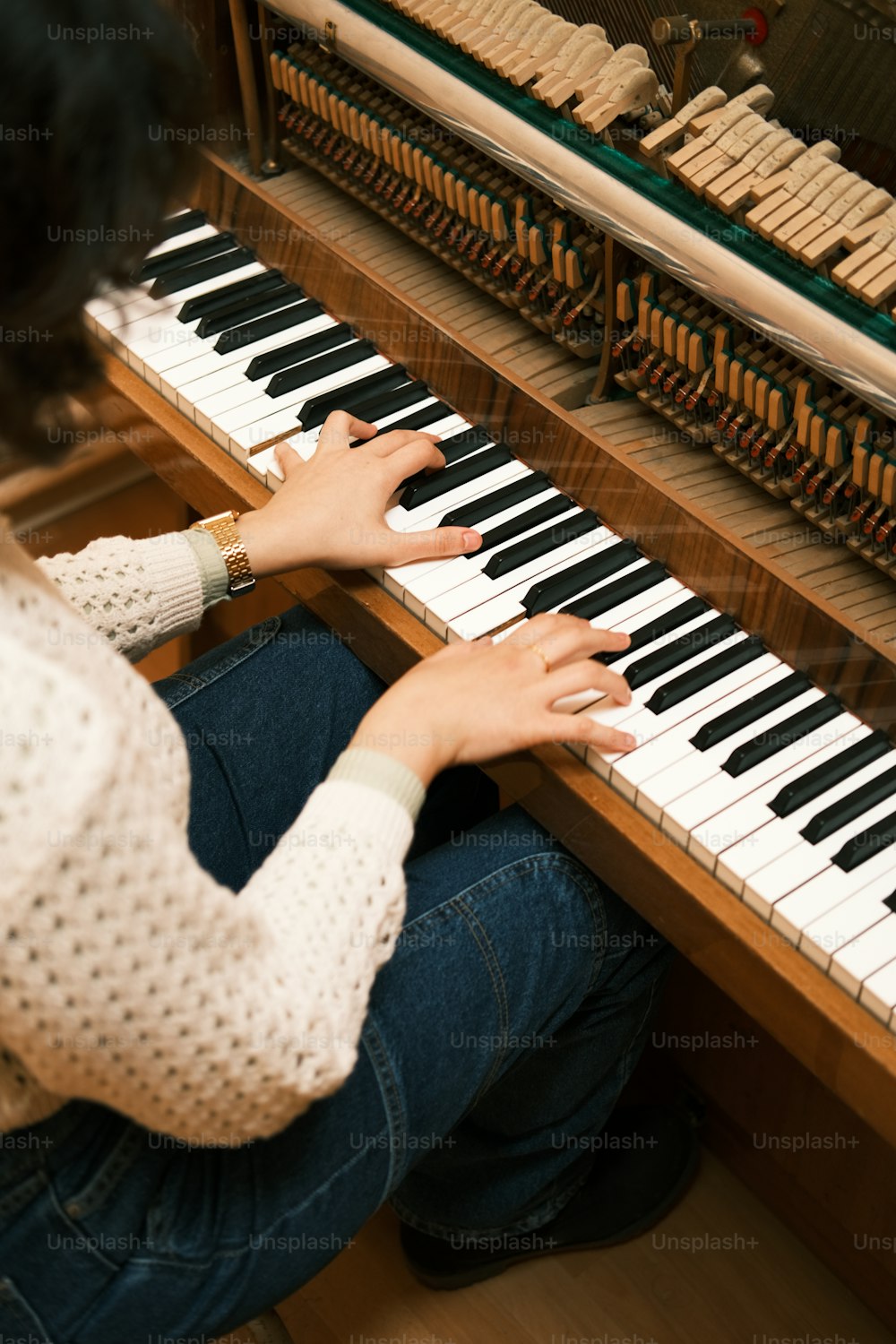uma mulher sentada em um piano com as mãos nas teclas
