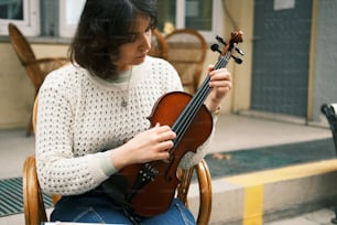 Eine Frau sitzt auf einem Stuhl und hält eine Geige in der Hand