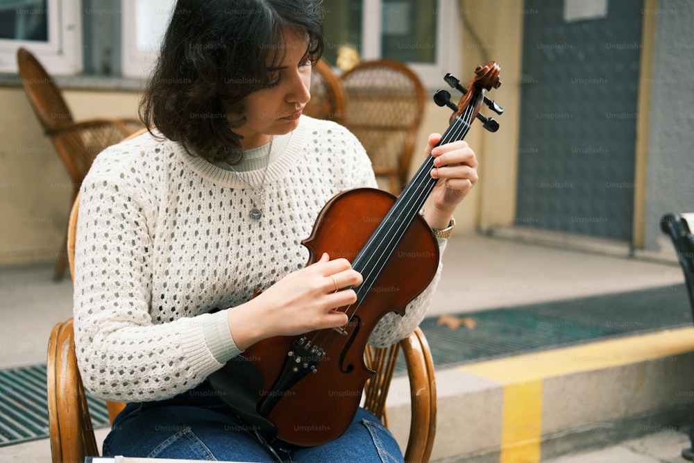 a woman sitting in a chair holding a violin