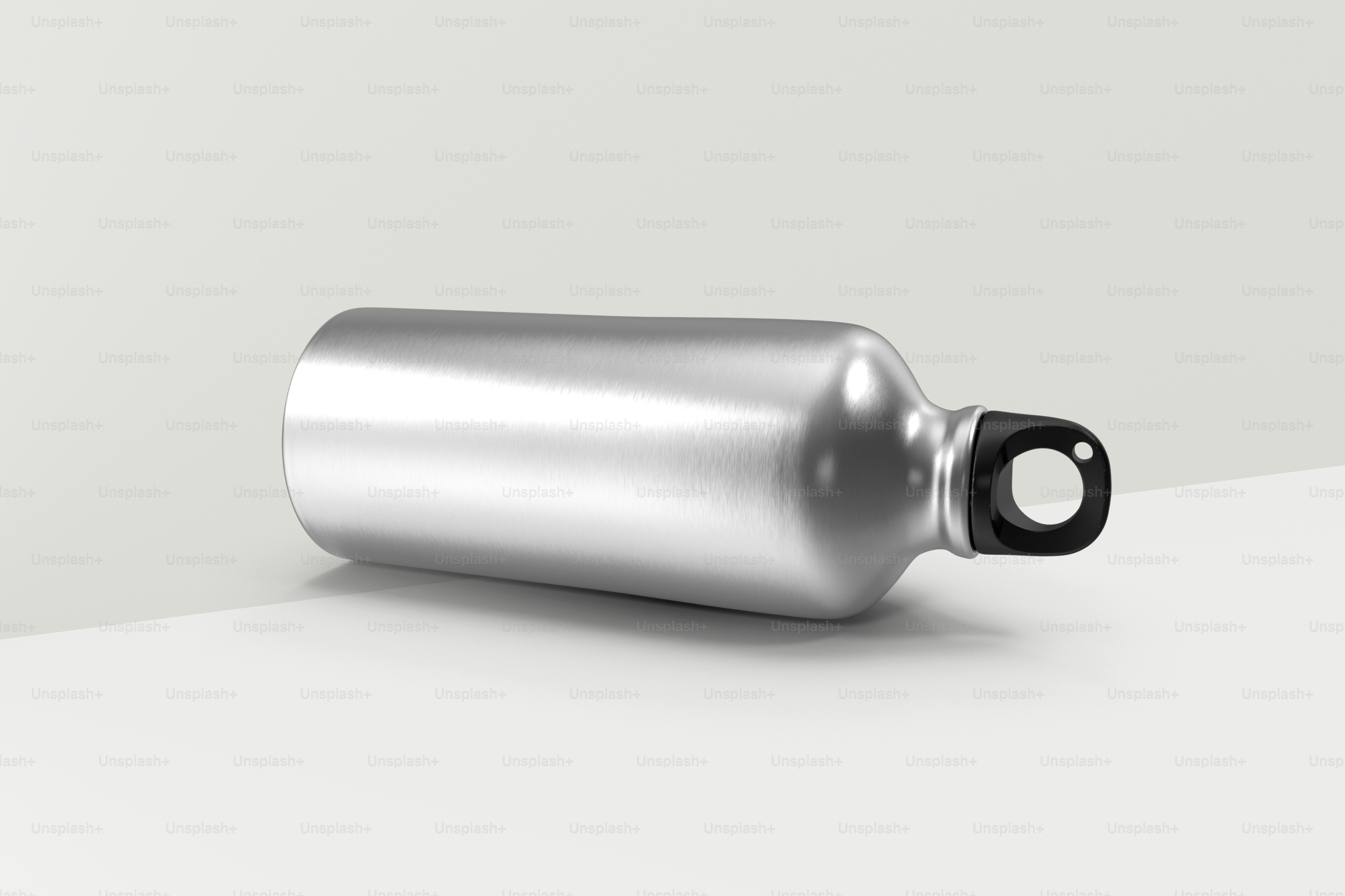 a silver bottle with a black cap on a white surface