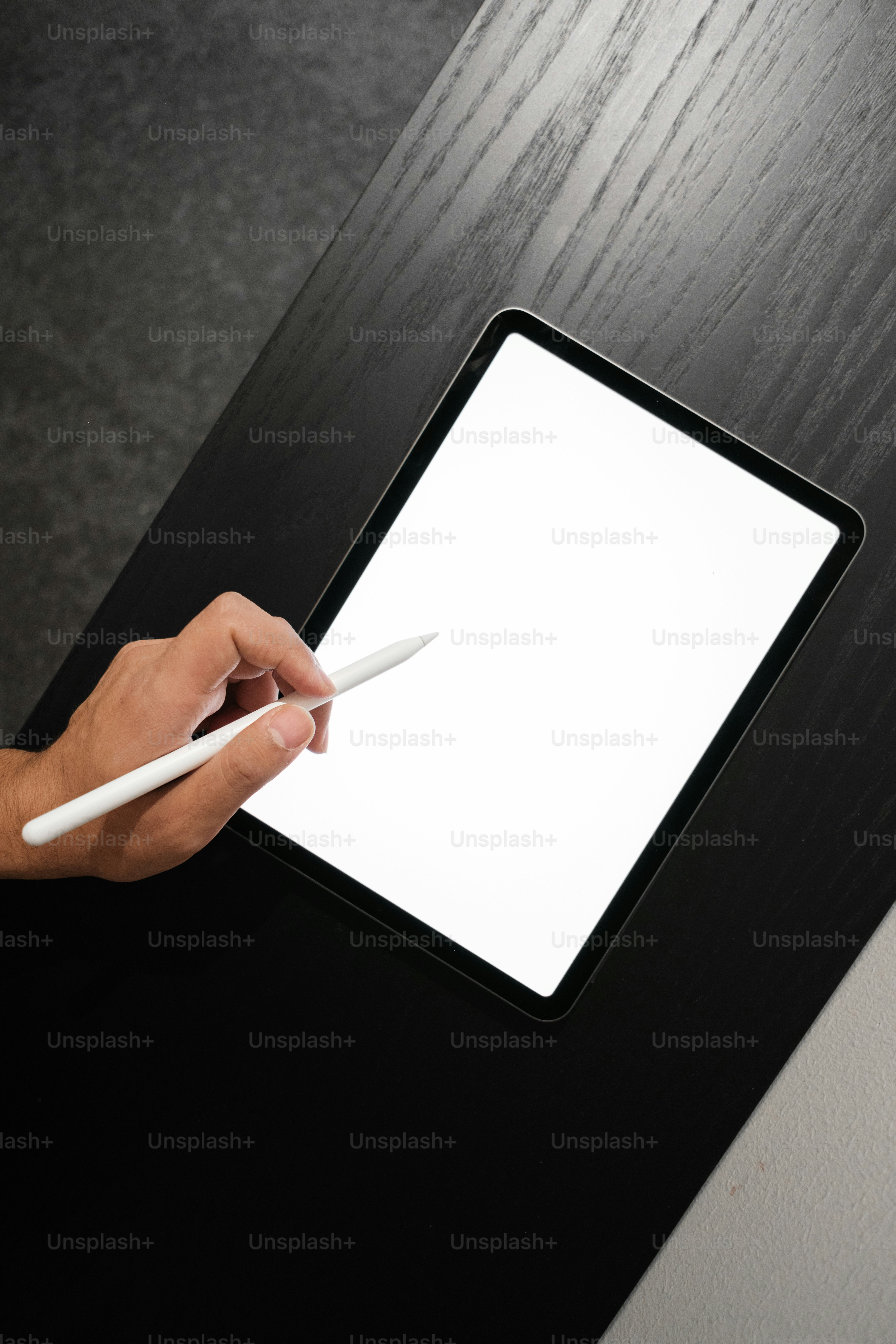 a person holding a pen and writing on a tablet
