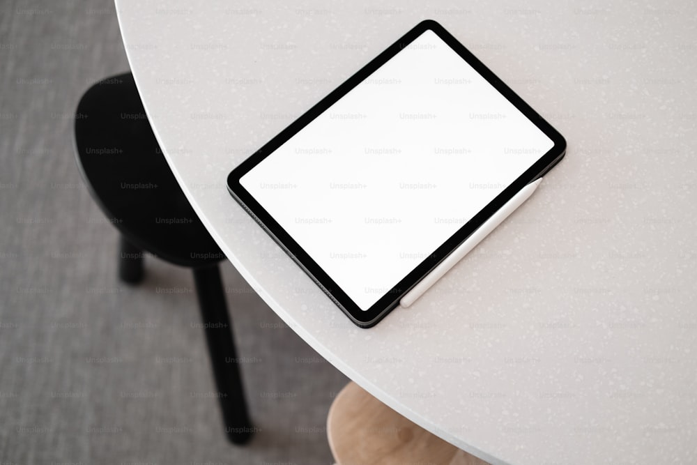 une tablette posée sur une table blanche