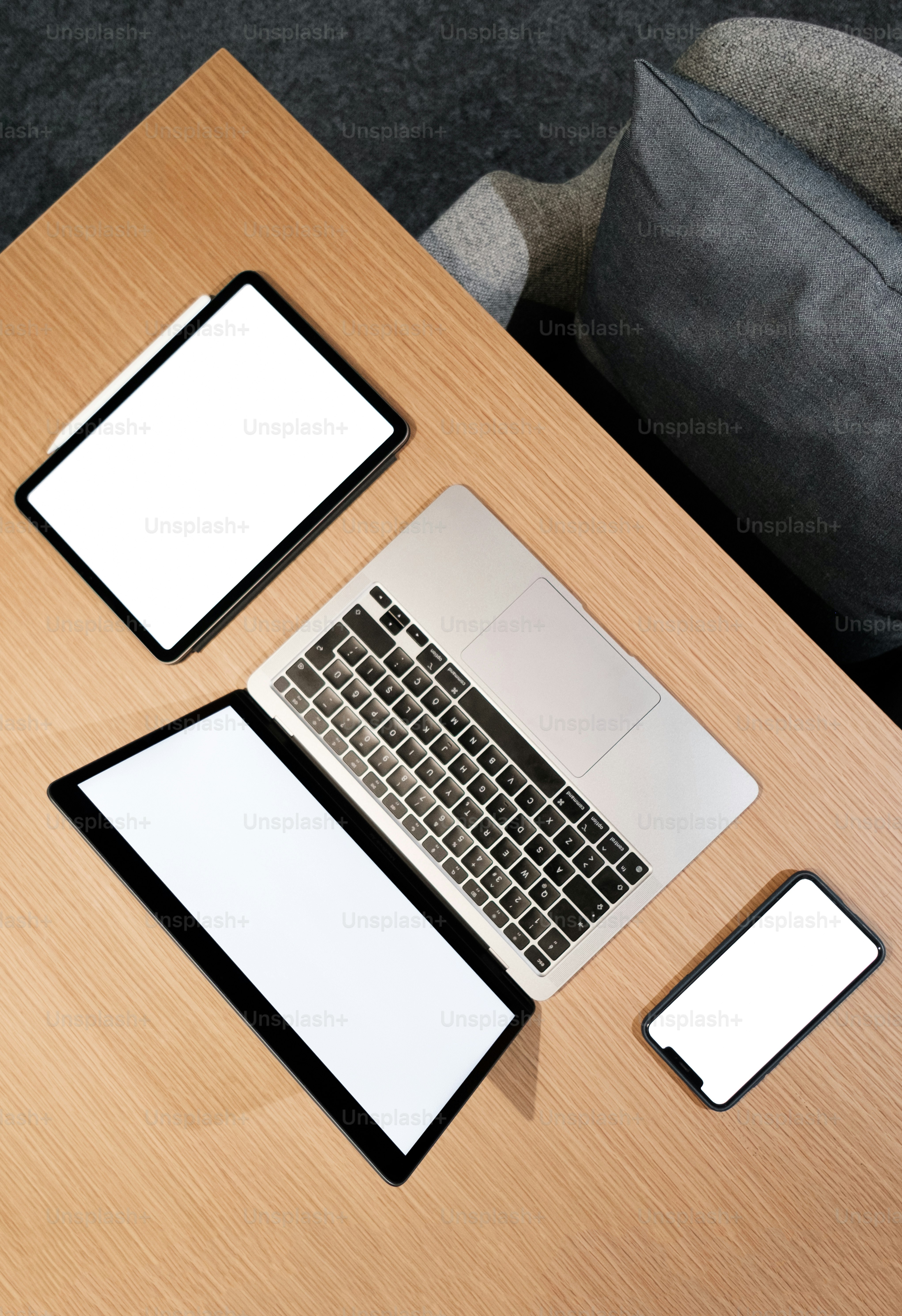 meja kayu di atasnya dengan komputer laptop di sebelah ponsel pintar
