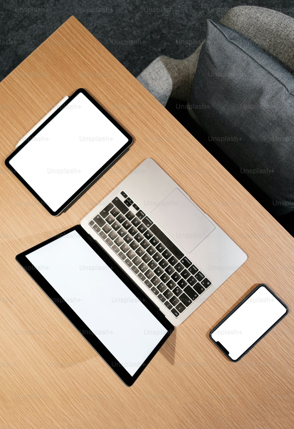 uma mesa de madeira coberta com um computador portátil ao lado de um telefone inteligente