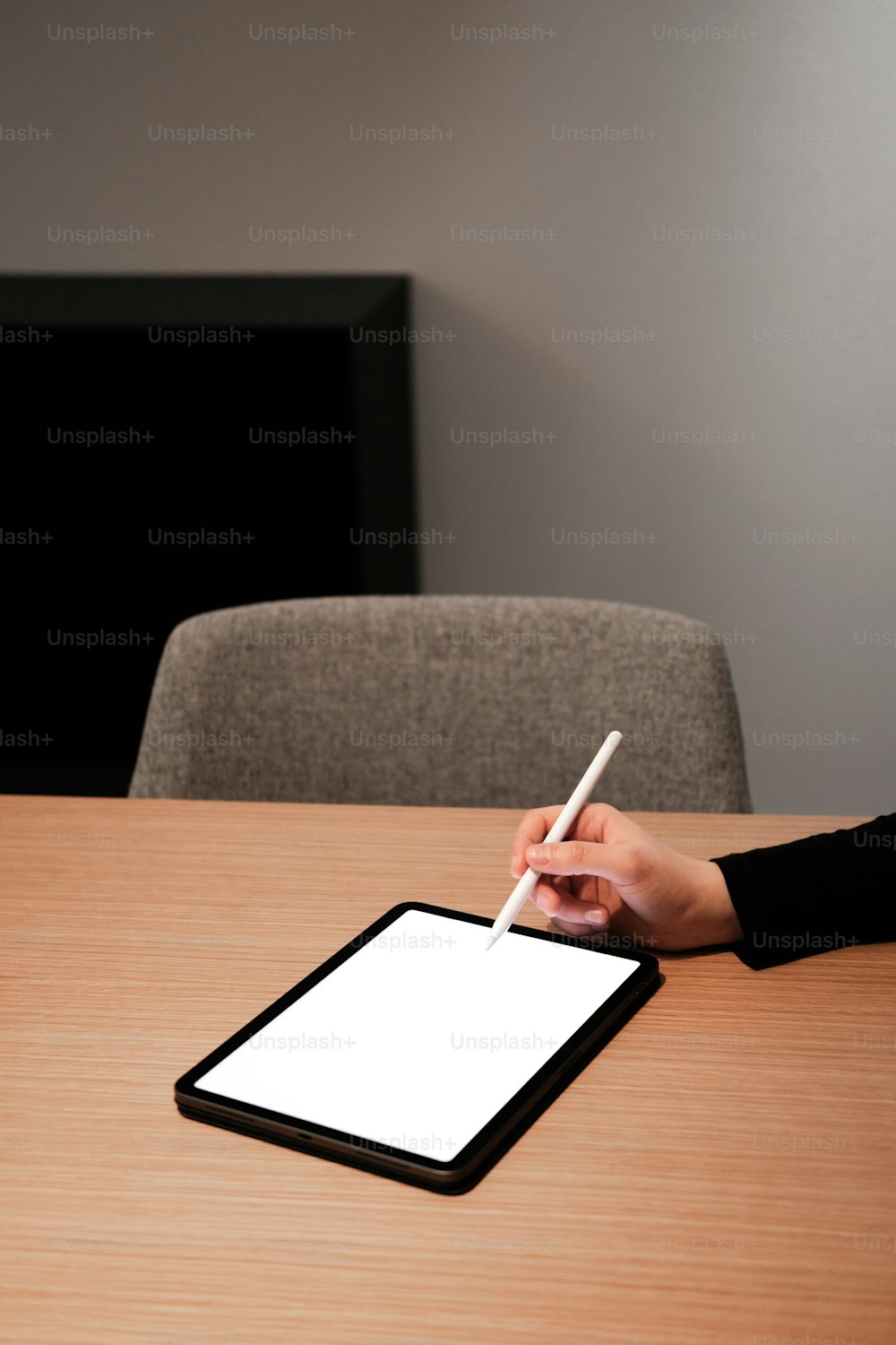 uma pessoa segurando uma caneta e escrevendo em um tablet