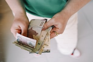 uma pessoa segurando um monte de dinheiro em suas mãos