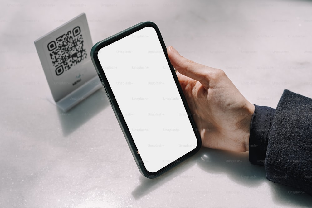une personne tenant un téléphone cellulaire avec un écran blanc