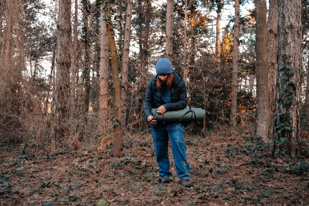 a man in a blue hat is holding a bag in the woods