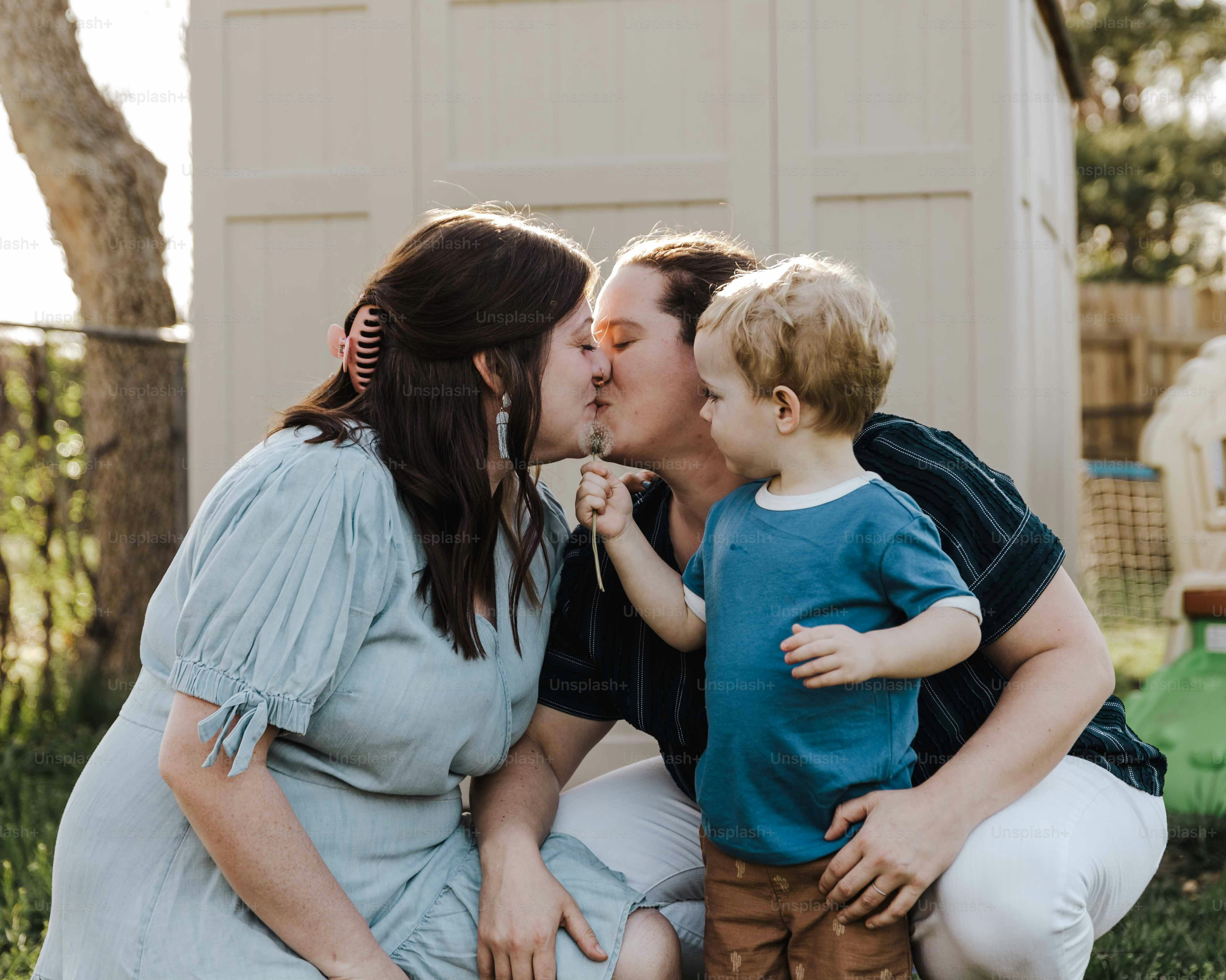 a woman kissing a small boy on the cheek