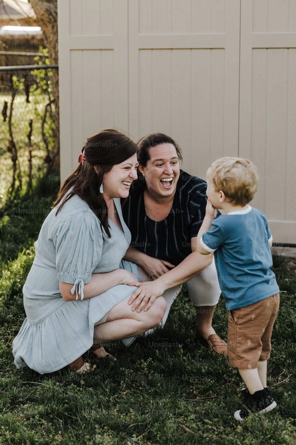 a man, woman, and child laughing together in the grass