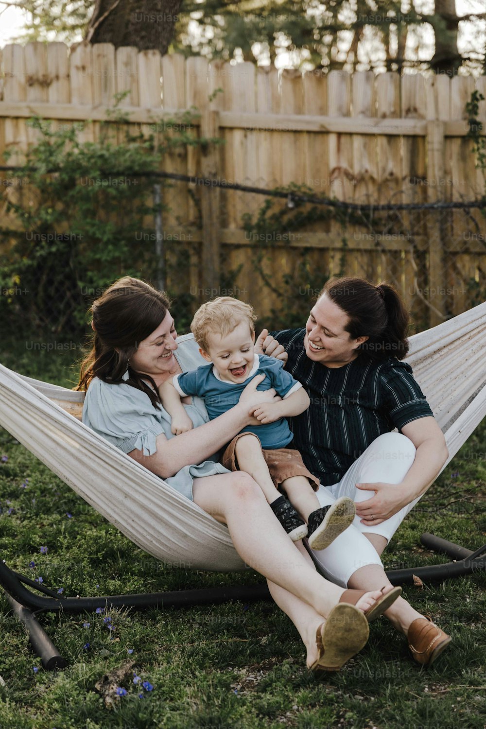 a woman and two children sitting in a hammock