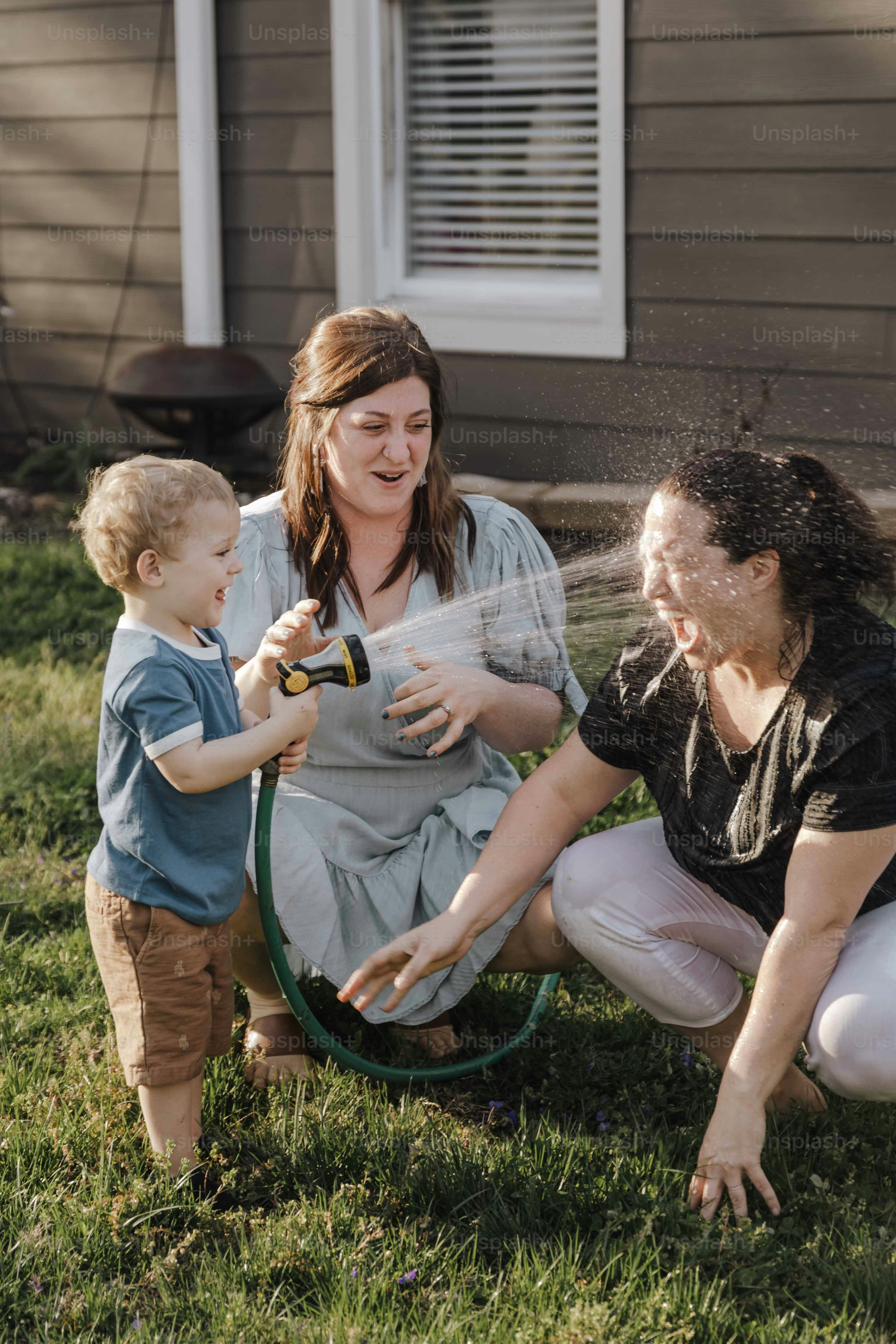 a woman and a child playing with a hose