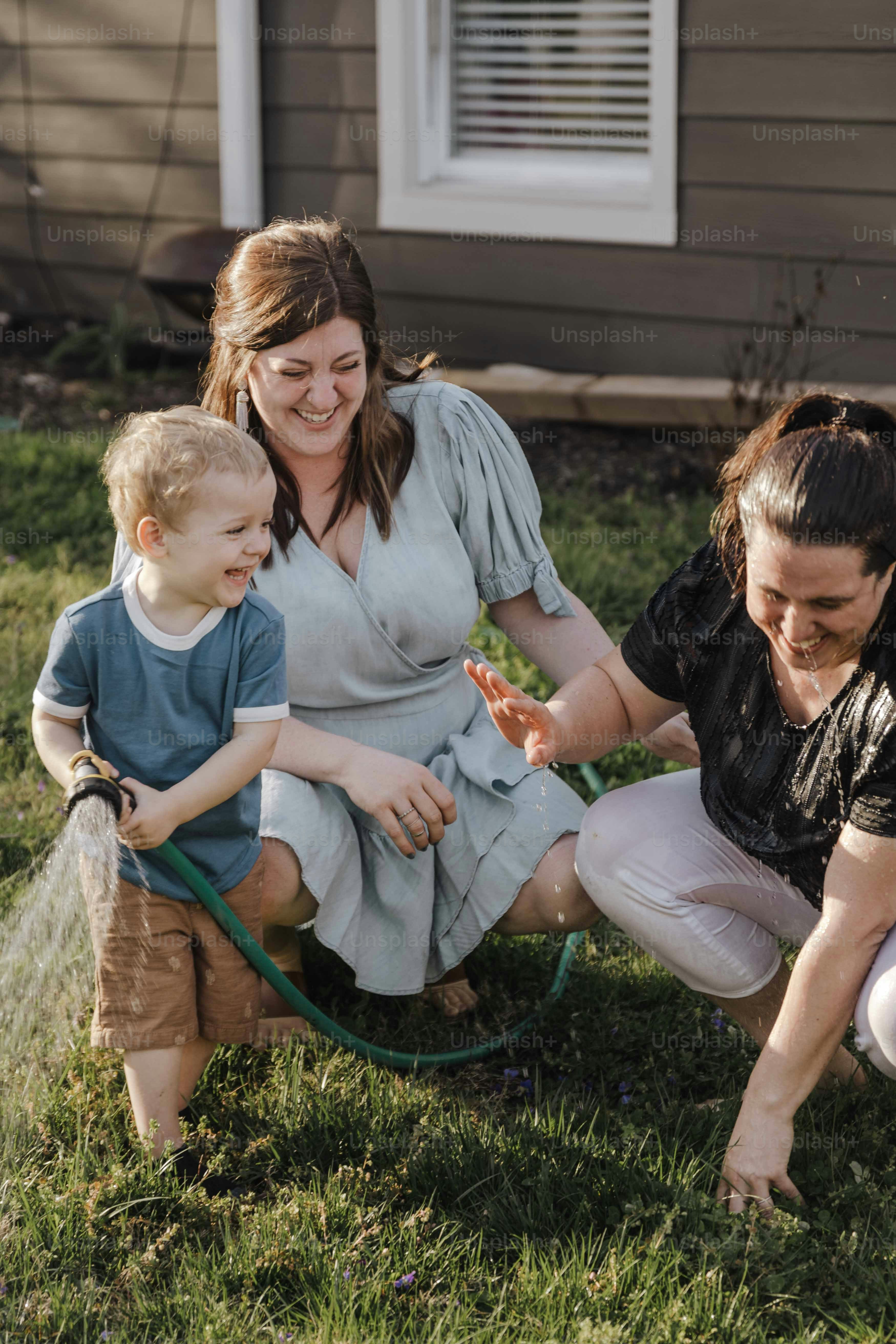 a woman and a child are playing with a hose
