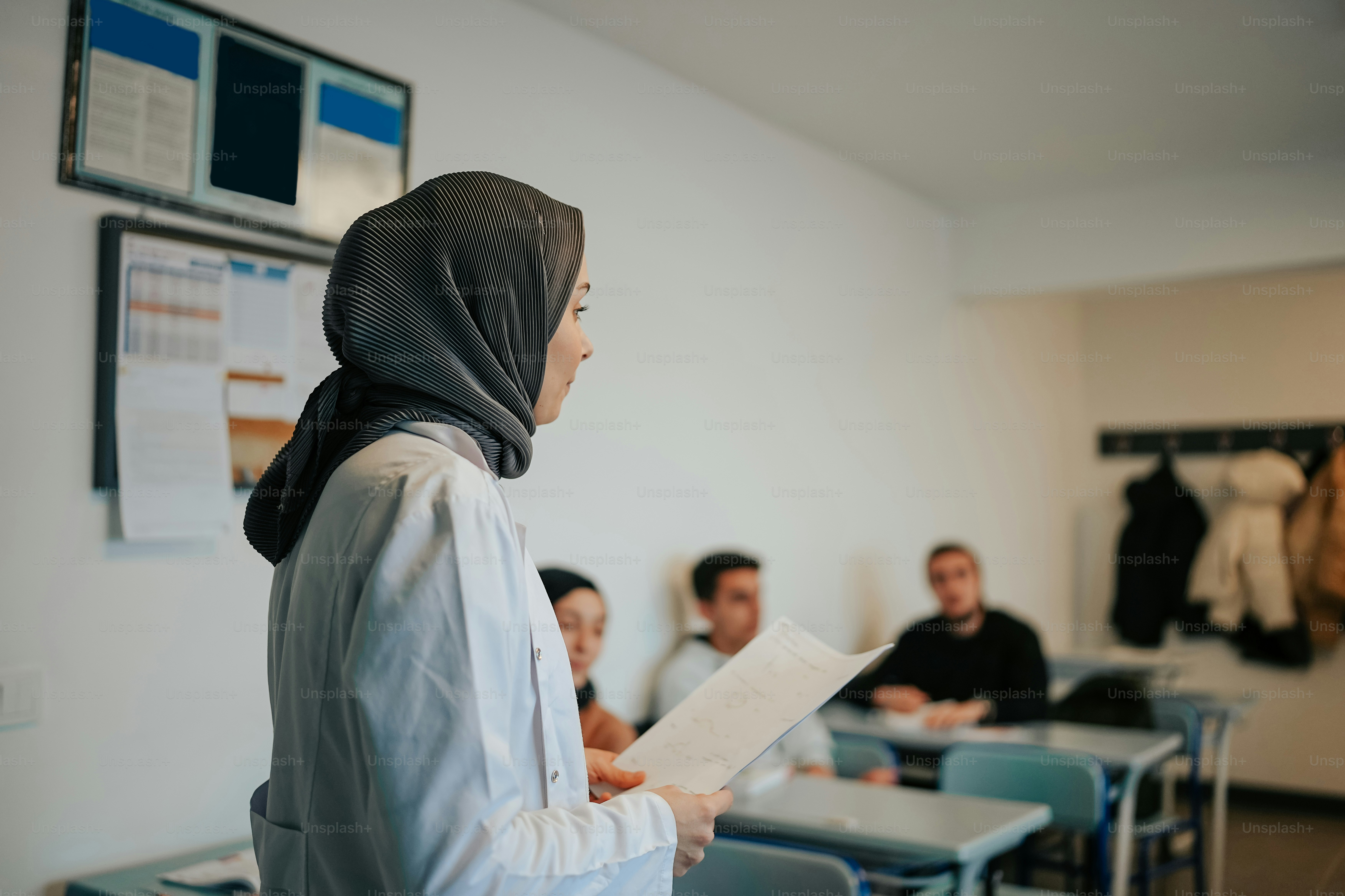 Une femme en hijab debout dans une salle de classe