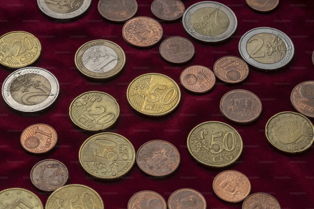 um monte de moedas diferentes em um pano vermelho
