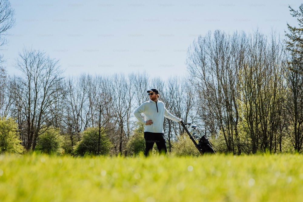 a man standing in a field with a golf bag
