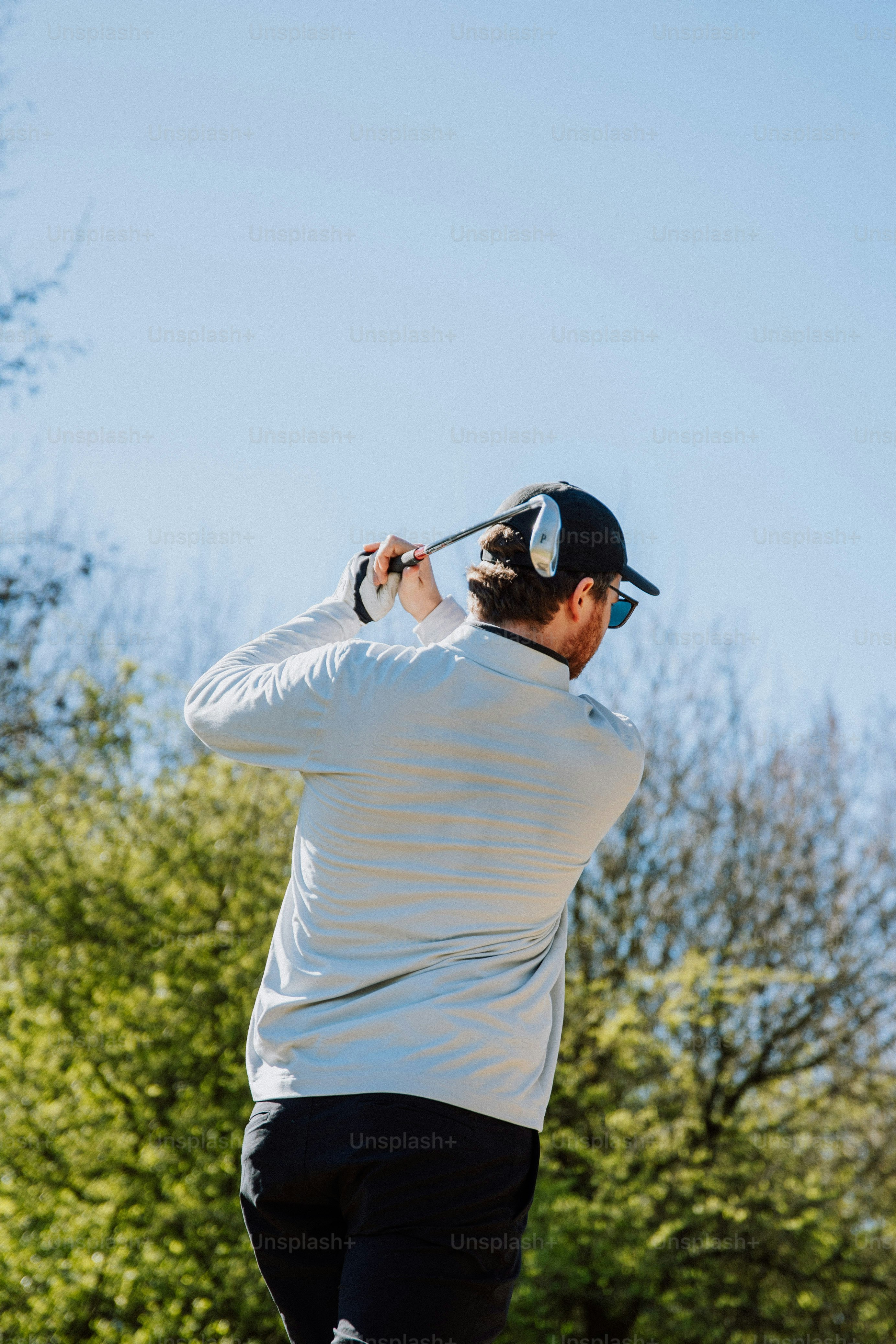 a man swinging a golf club on a sunny day