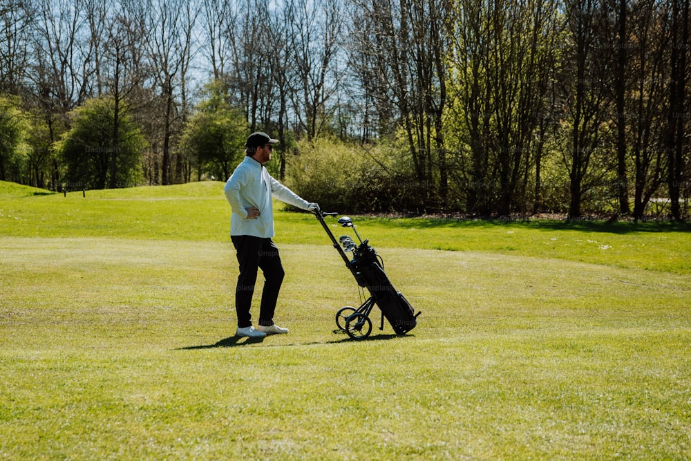 Un hombre sosteniendo un palo de golf y un carrito de golf