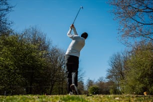 a man swinging a golf club on a sunny day