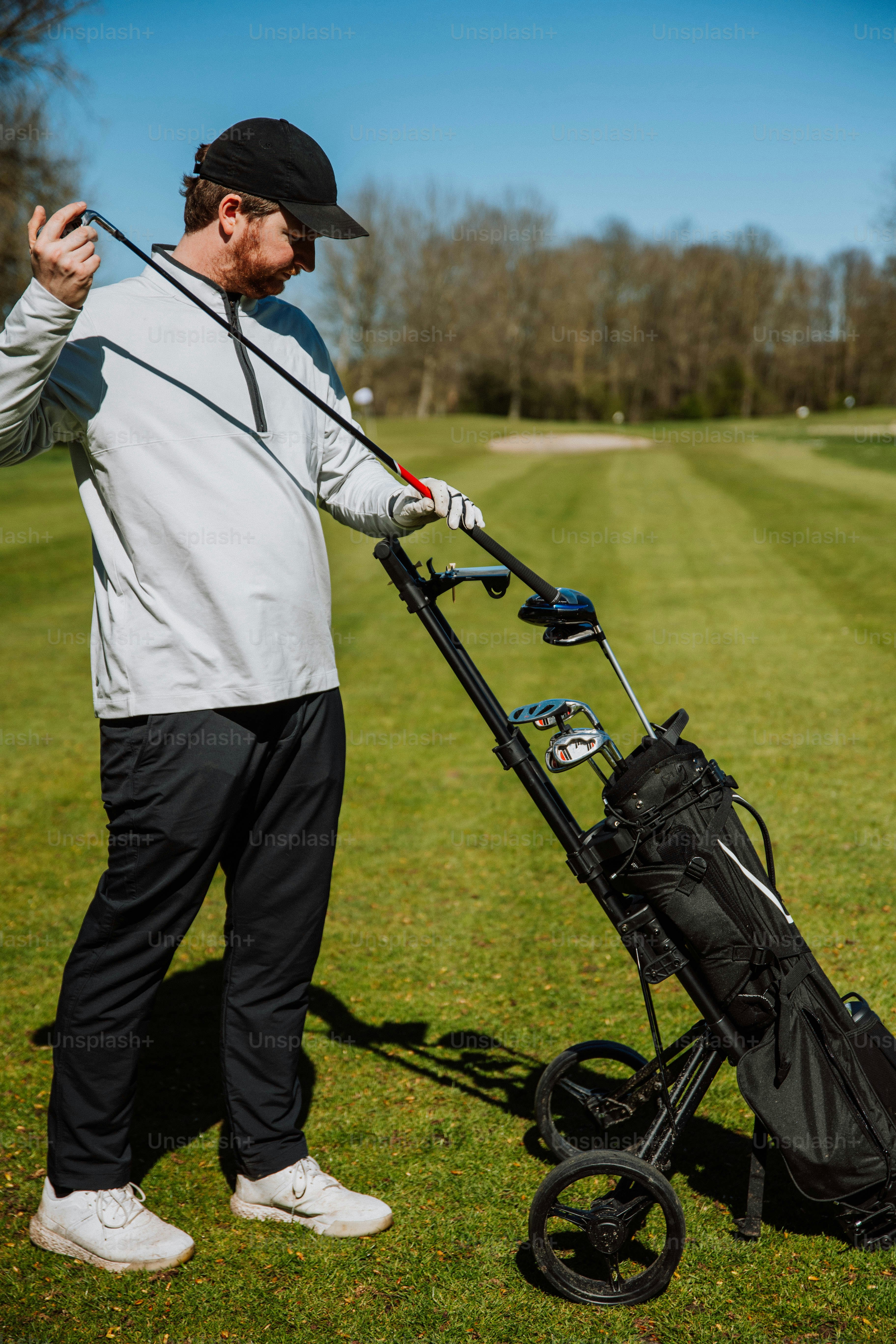 a man holding a golf club next to a golf cart