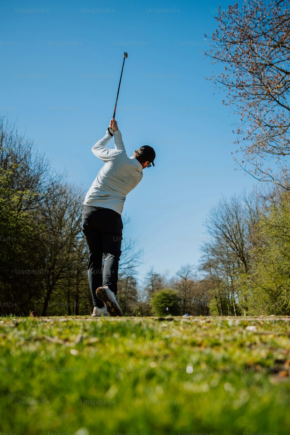 a man swinging a golf club in a park