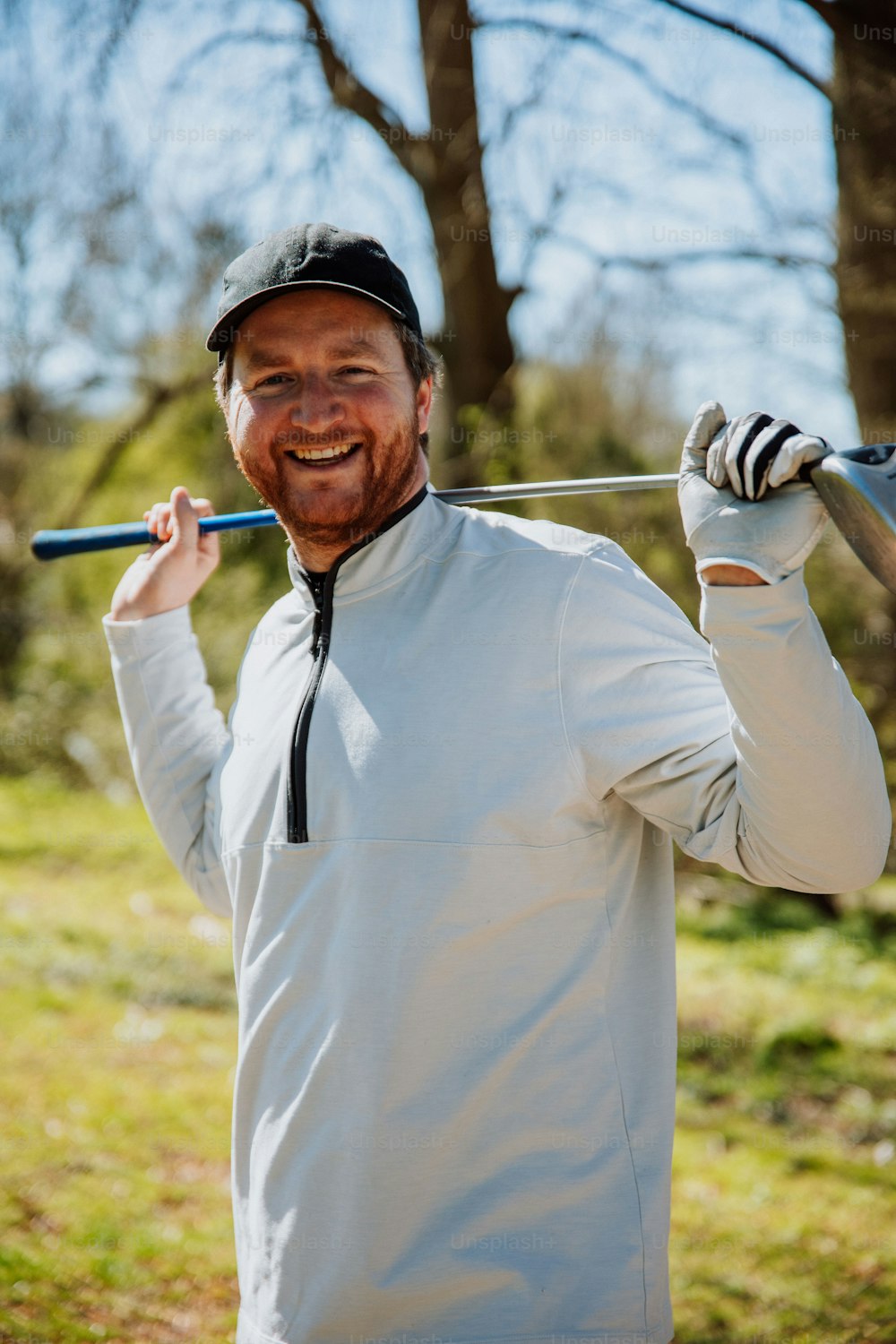 Un hombre sosteniendo un palo de golf y sonriendo