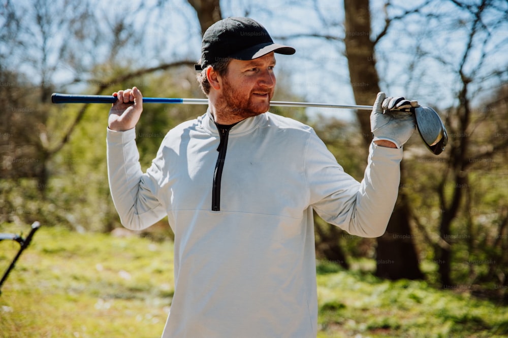 Un hombre sosteniendo un palo de golf en su mano derecha