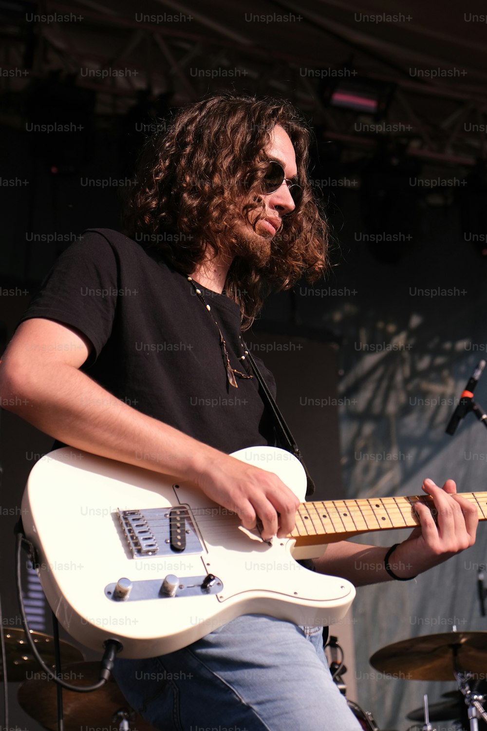 um homem com cabelos compridos tocando uma guitarra branca