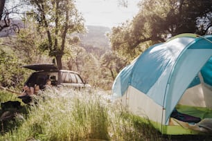 a person sitting in a tent next to a car