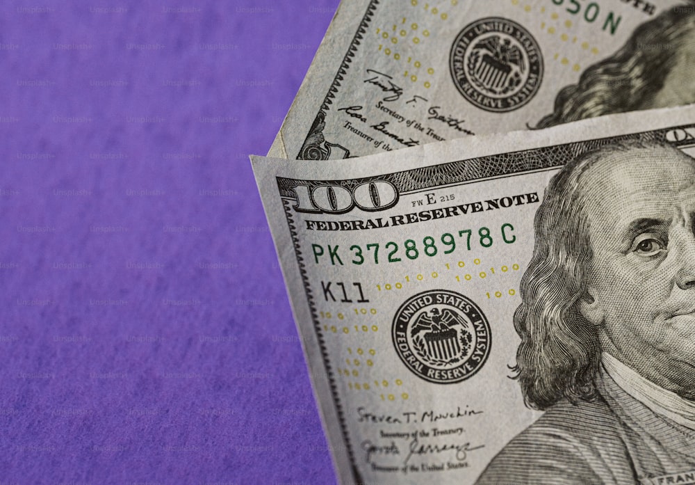 Ein Stapel Hundert-Dollar-Scheine auf lila Hintergrund