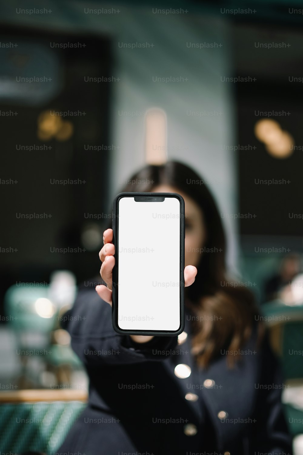 a woman holding up a smart phone with a white screen