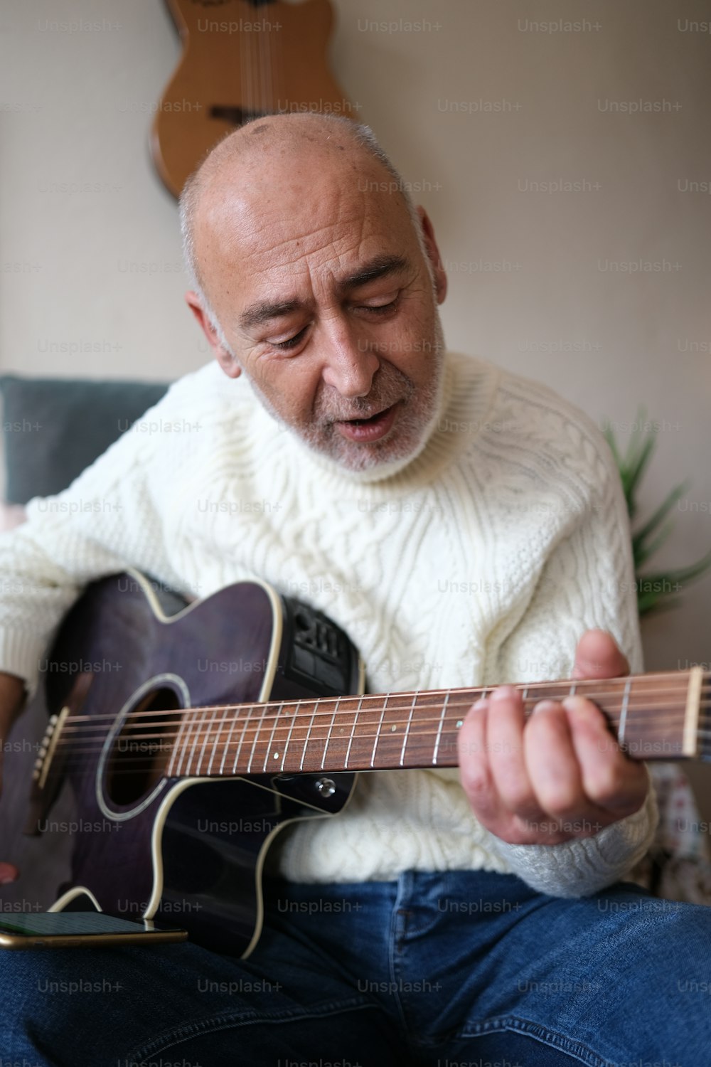 Ein Mann, der auf einer Couch sitzt und Gitarre spielt