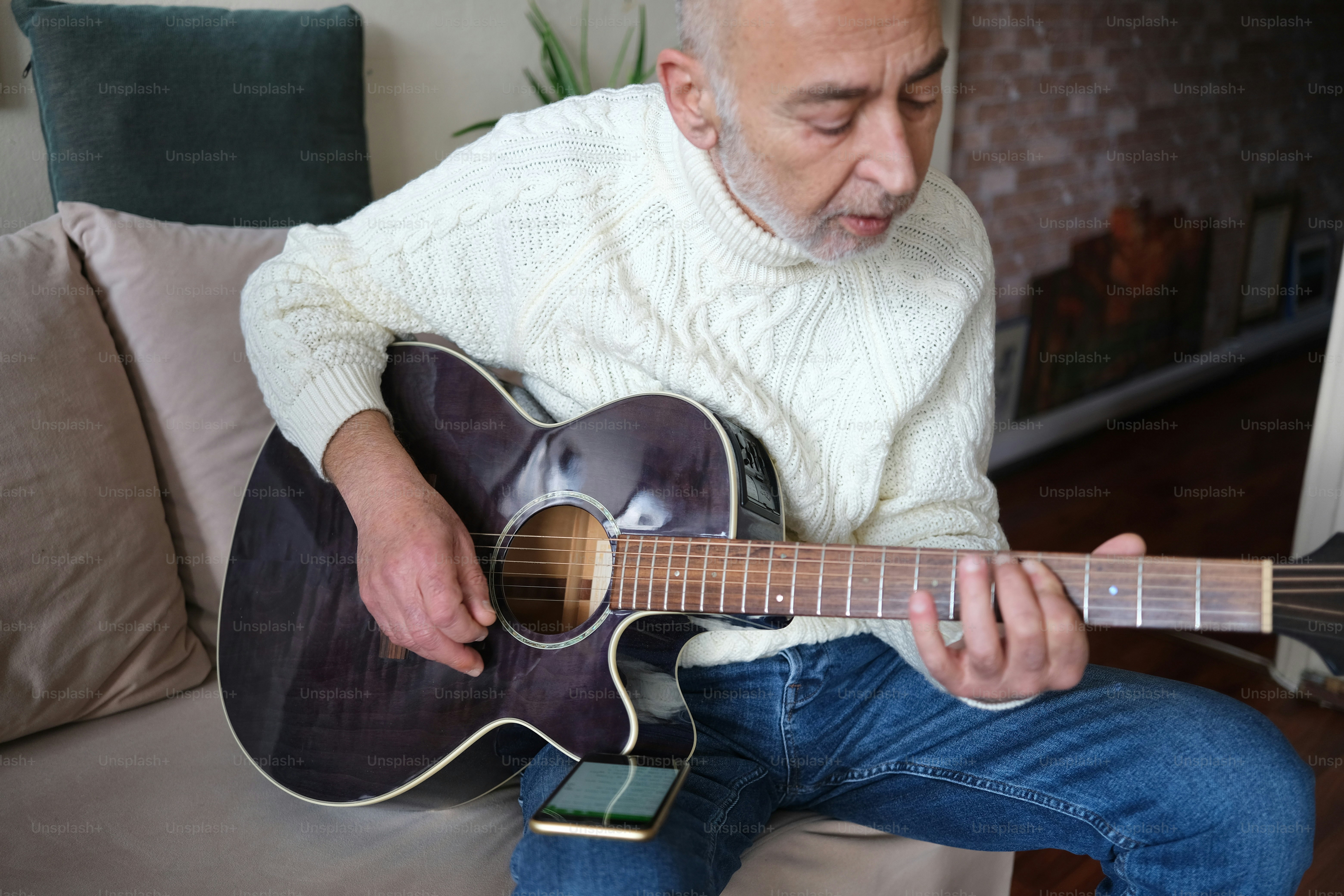 A man sitting on a couch playing a guitar photo – Music Image on Unsplash