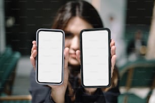 한 여성이 ��얼굴 앞에 두 개의 휴대폰을 들고 있다