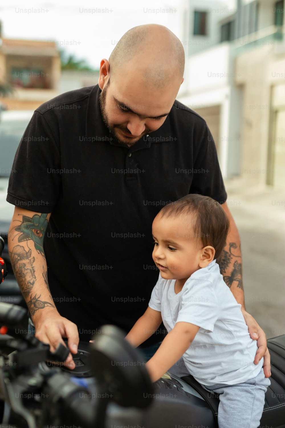 a man with a bald head and a small child on a motorcycle