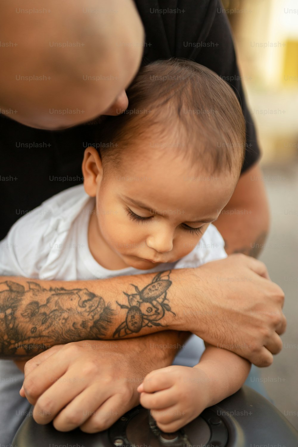 팔에 문신이 있는 아기를 안고 있는 남자