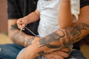 a man holding a child with a tattoo on his arm