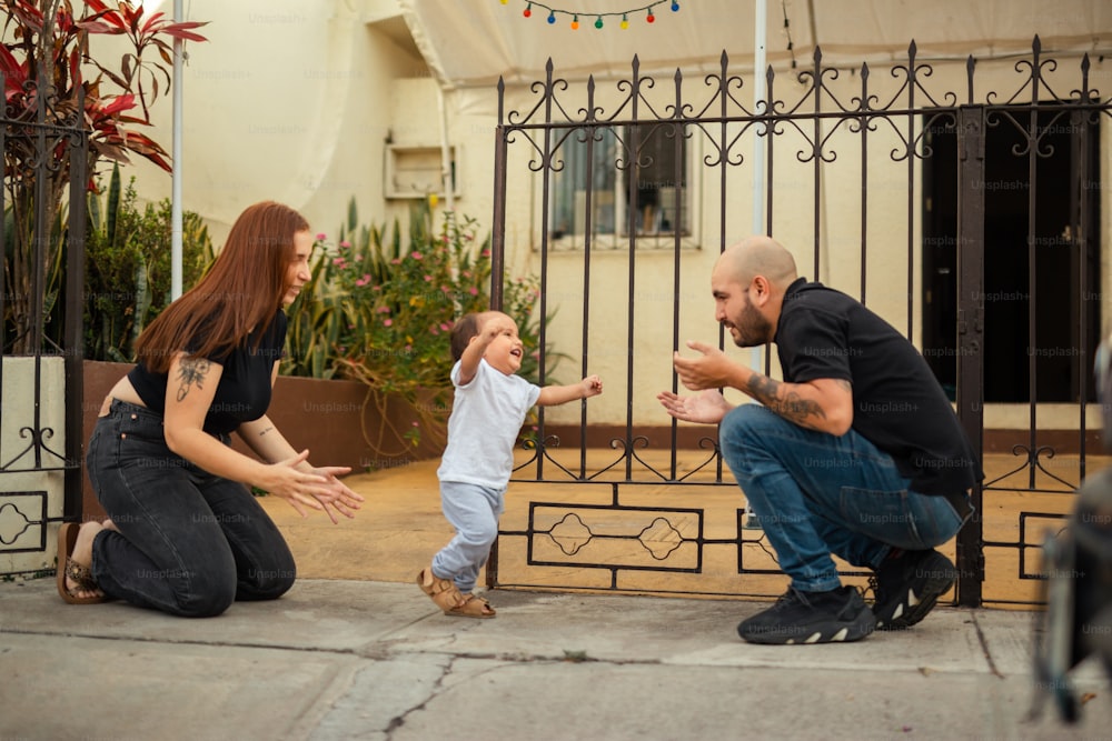 a man, woman, and child playing with each other in front of a gate