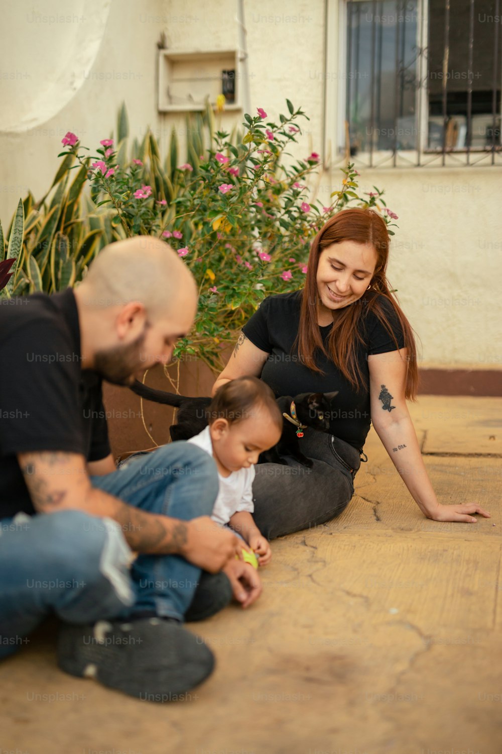 a man, woman and baby sitting on the ground