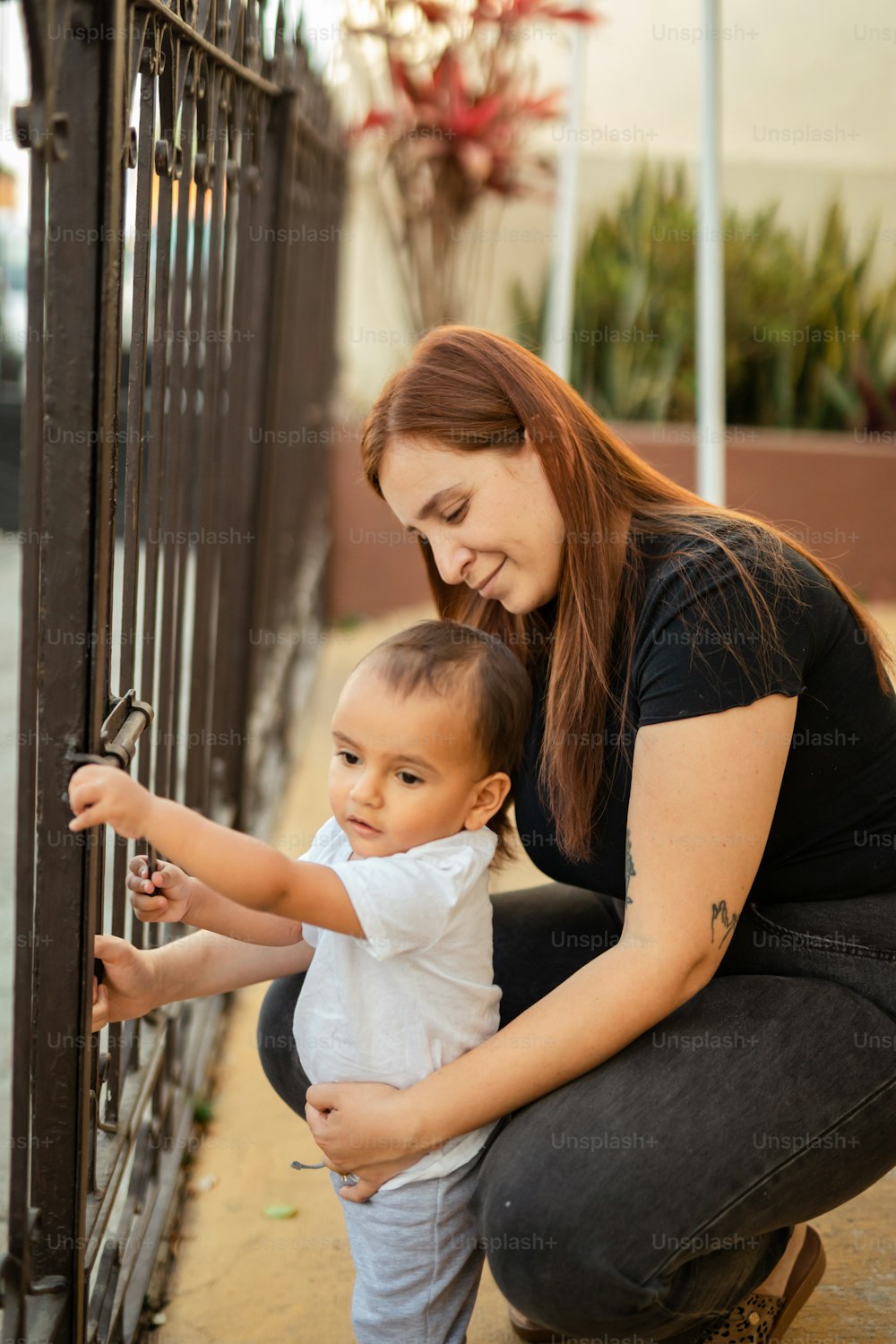 a woman holding a small child near a fence