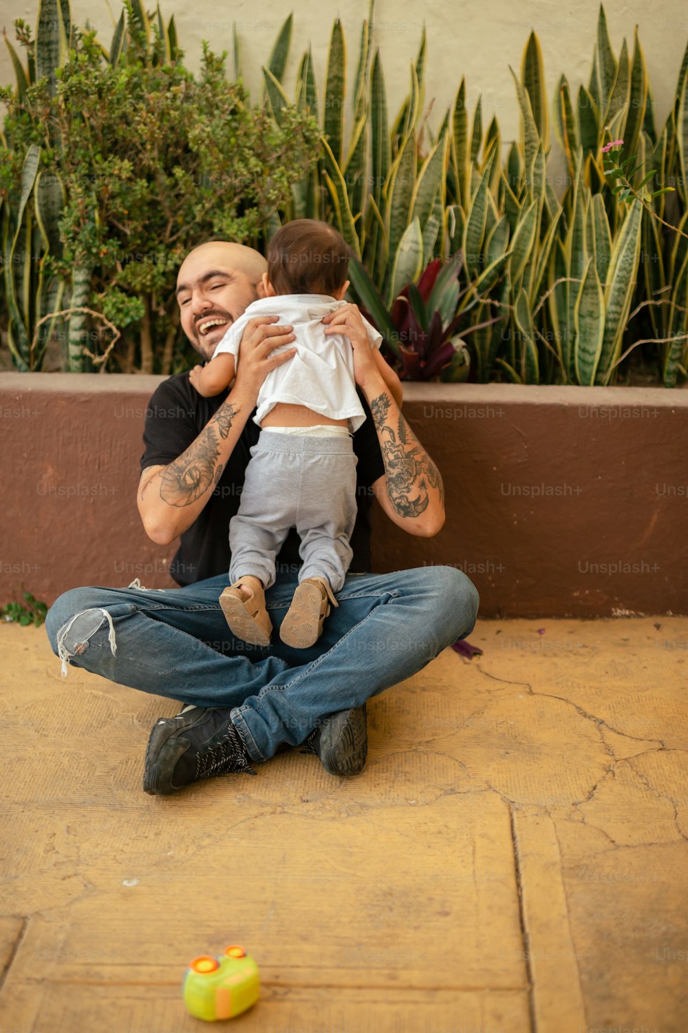 un uomo seduto a terra con in braccio un bambino