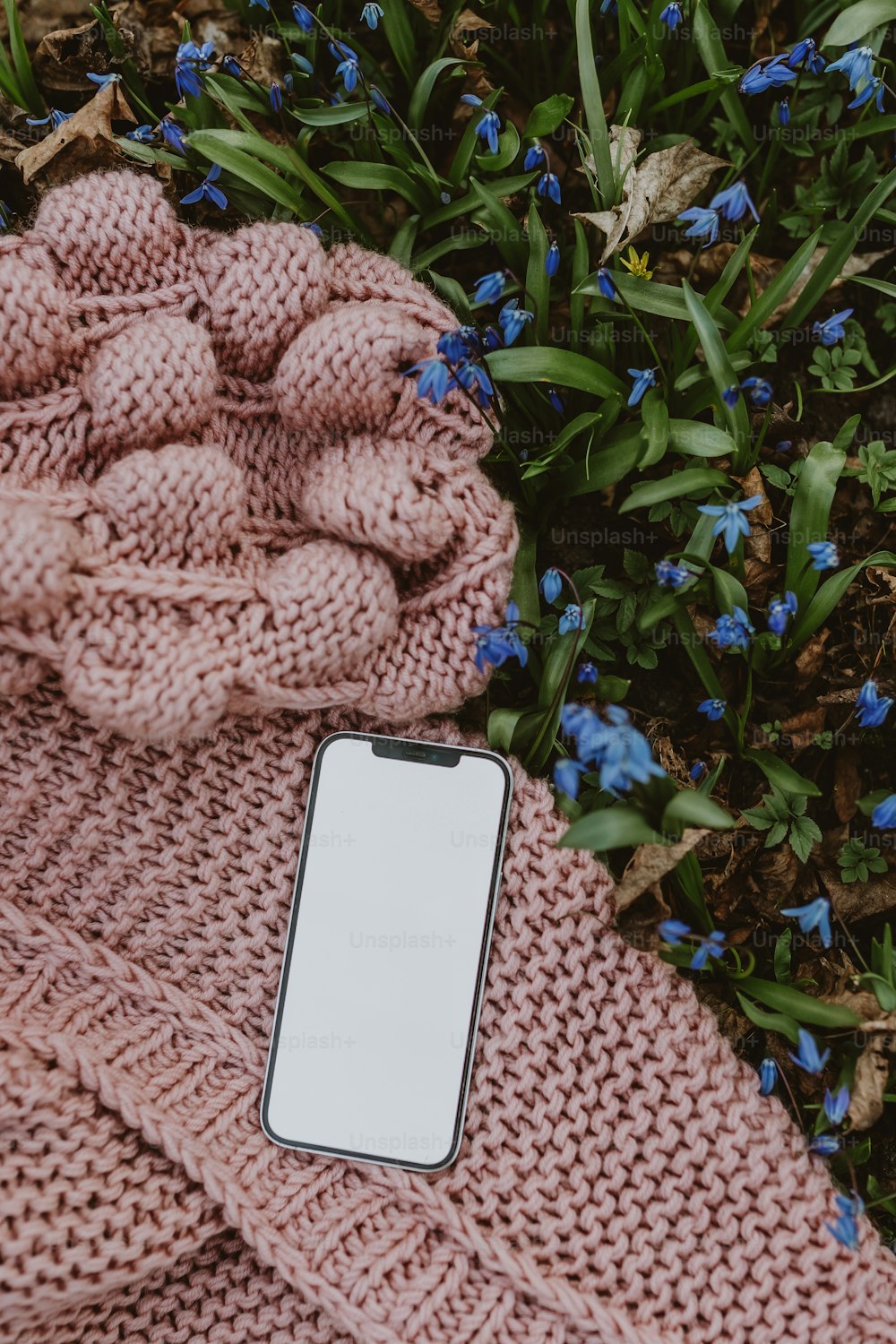 분홍색 담요 위에 앉아있는 휴대 전화