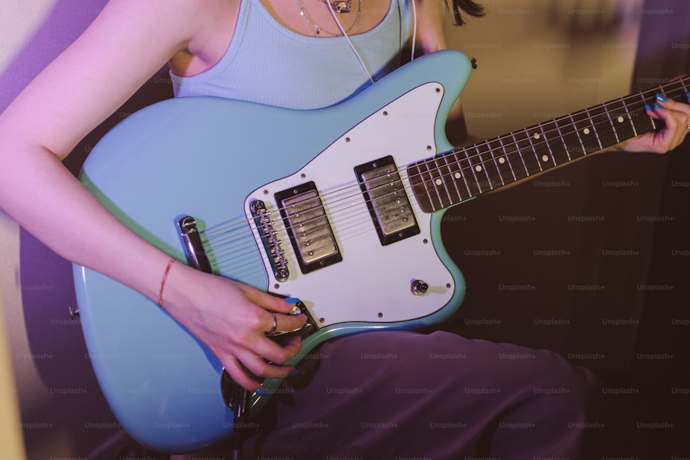 a woman is holding a blue electric guitar