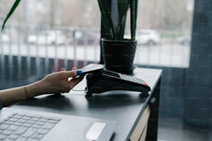 a person using a phone on a desk next to a laptop