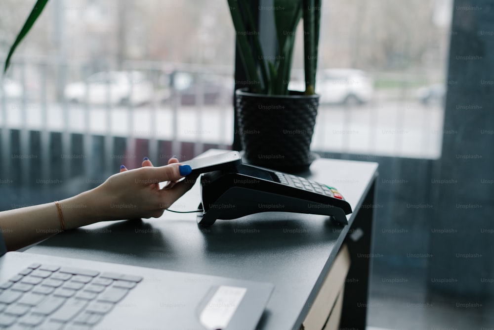 a person using a phone on a desk next to a laptop