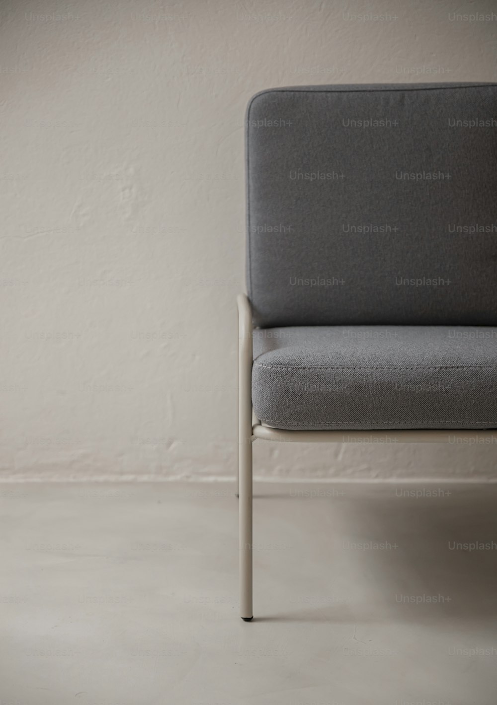 uma cadeira cinza sentada na frente de uma parede branca