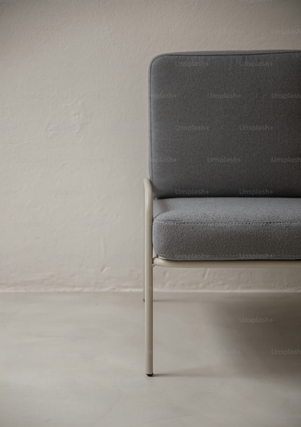 a gray chair sitting in front of a white wall