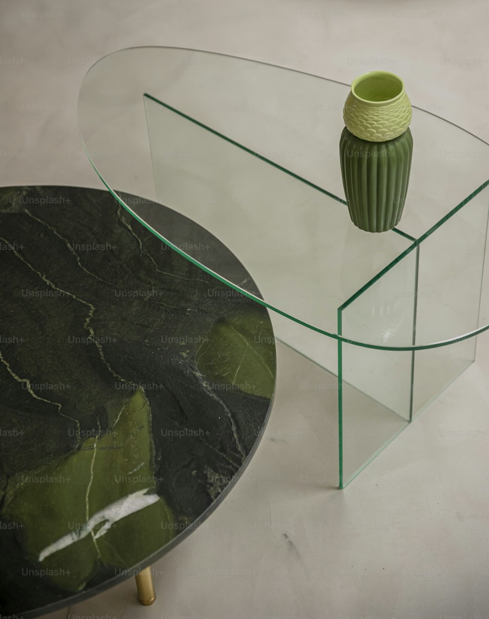 a green vase sitting on top of a glass table