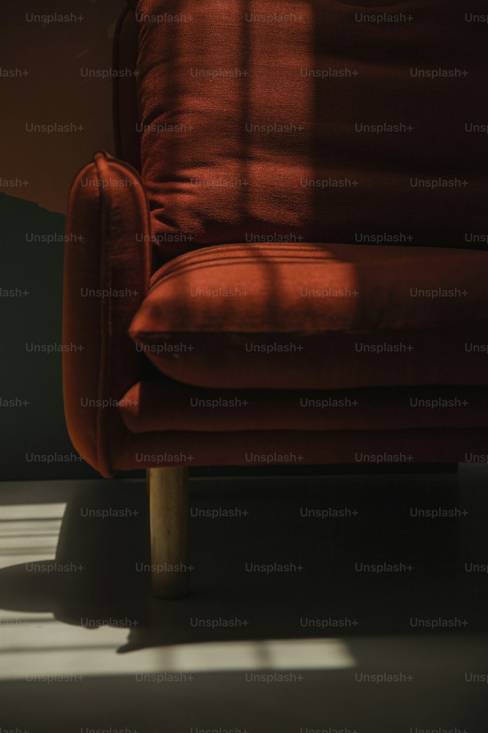 ein roter Stuhl, der in einem Raum neben einem Fenster sitzt